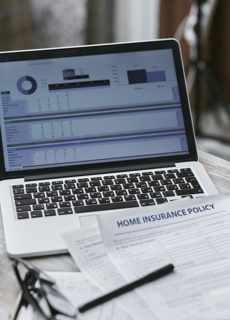 The image features a close-up of a laptop placed on a wooden table, displaying various charts and graphs related to data analysis or financial reports, with a focus on bar and pie charts. In the foreg